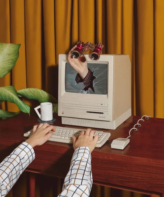 Cenário de fotografia com tela de computador quebrada, binoculo e mãos digitando com cortina amarela ao fundo