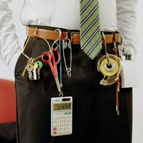 soluções expansing Homem com roupa social e um cisto com chaves, durex, calculadora e outras coisas penduradas